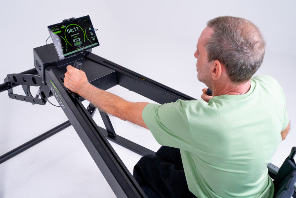 Man using rowing machine with tablet display.