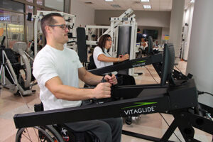 Man exercising with resistance machine in a gym setting.